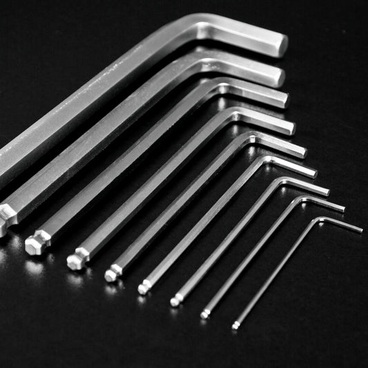 A set of silver metal hex wrenches in different sizes arranged diagonally on a dark black background.