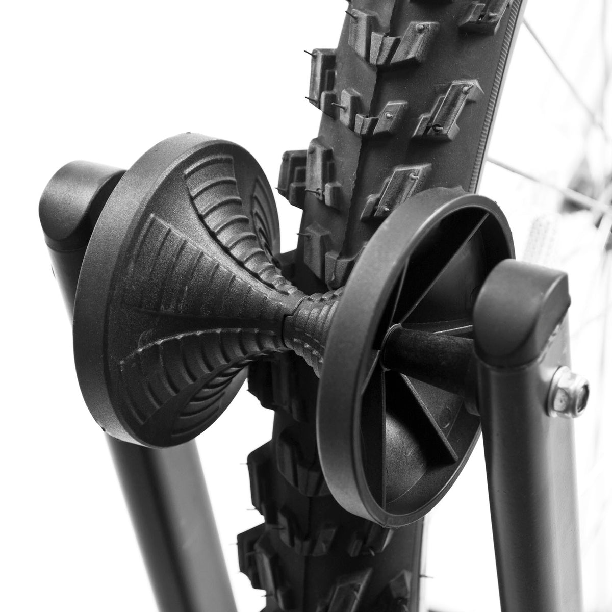 Close-up of a black bicycle tire mounted on a black wheel hub or rim, photographed against a bright white background.