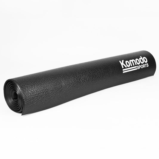 A rolled-up black textured floor mat with the brand name 'Komodo SPORTS' printed in white on the side, set against a plain white background.
