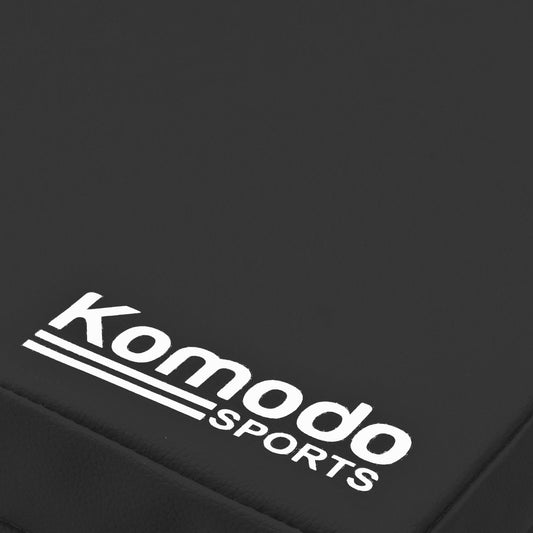Close-up of a black textured surface with a white Komodo Sports logo printed on it.
