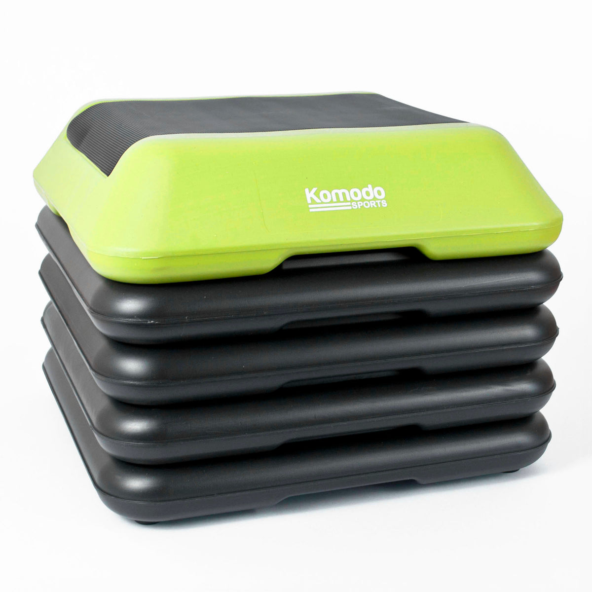 A stack of five step platforms, with the top step in lime green and black showing the white 'Komodo Sports' logo, on a white background.