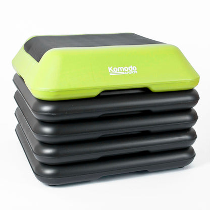 A stack of five step platforms, with the top step in lime green and black showing the white 'Komodo Sports' logo, on a white background.