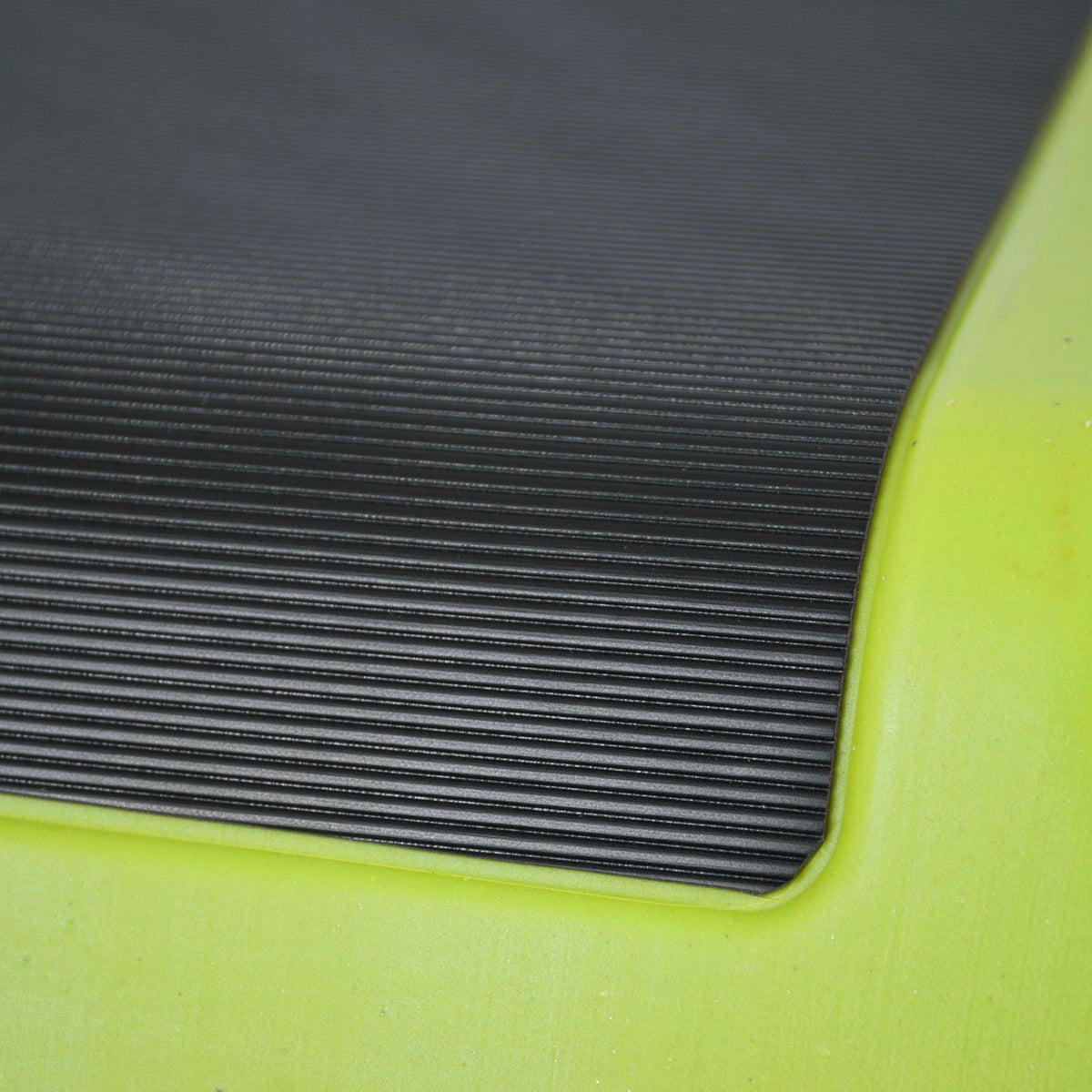 Close-up of a black ribbed textured mat or pad attached to a bright neon yellow-green frame or base.