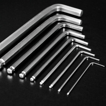 A set of silver metal hex wrenches in different sizes arranged diagonally on a dark black background.