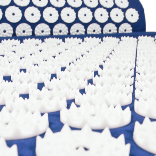 White massage foam roller tips arranged in rows on a dark blue surface, with a matching blue acupressure mat showing circular textured rollers.