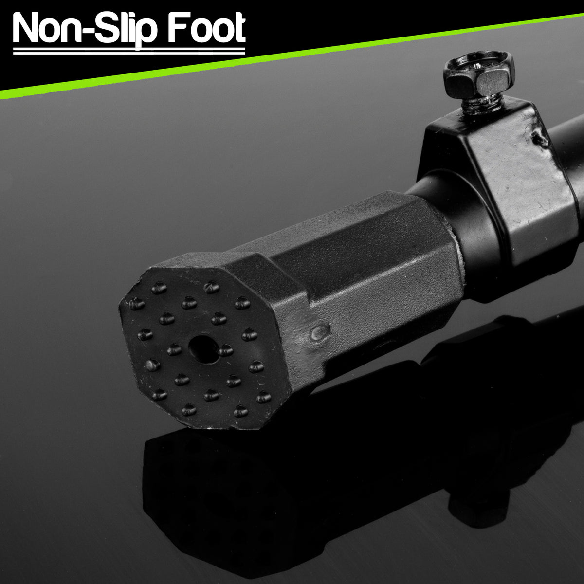 A close-up of a black non-slip foot pad on a bike kick stand with a textured, dotted surface and a hexagonal design, shown on a reflective dark background with a green and black 'Non-Slip Foot' banner at the top.