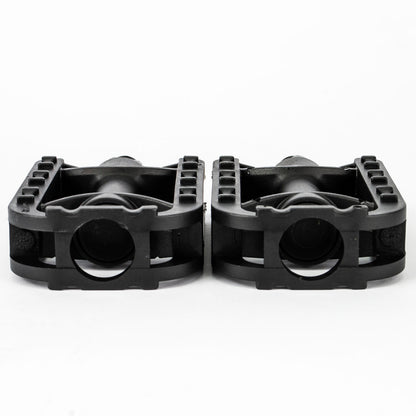 A pair of black plastic motorcycle or dirt bike foot pegs shown from the side against a plain white background.