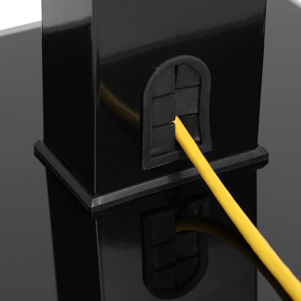 Close-up of a yellow cable being inserted into a black plastic outlet or connector on a glossy black surface.