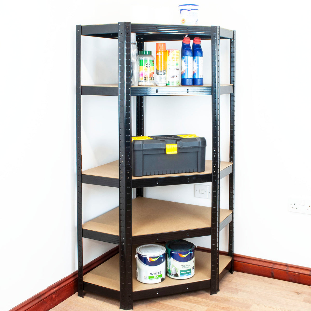 A 5-tier black metal shelving unit with brown particle boards, shown in a home environment with various household items on the shelves against a white wall.