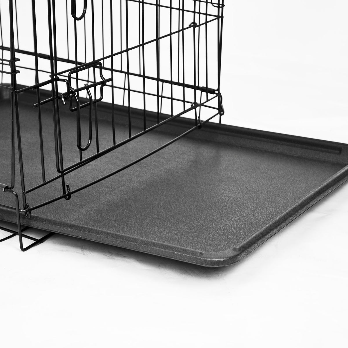 A removable tray being taken out of a metal pet crate