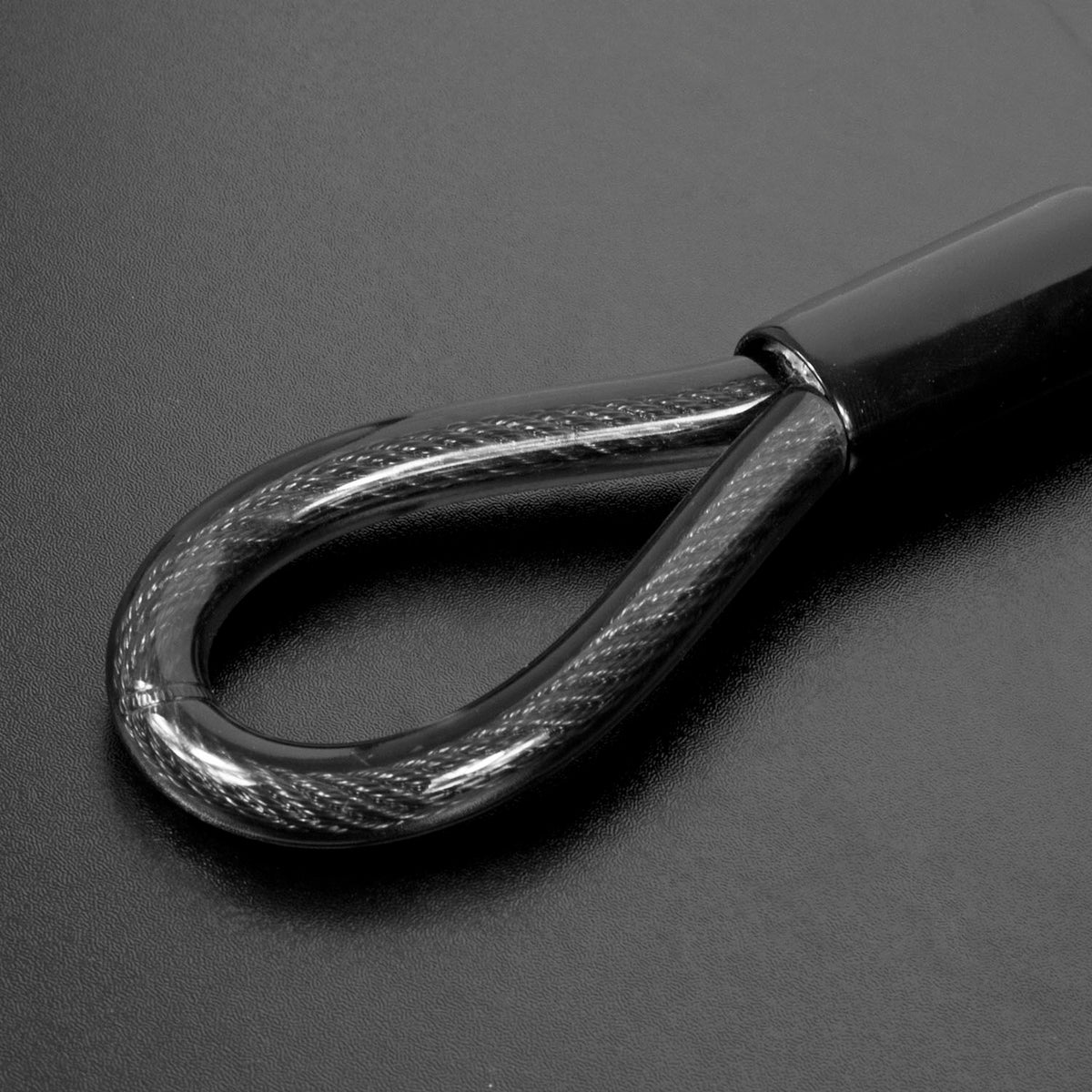 Close-up of a black loop and a glossy black grip, set against a dark gray background.