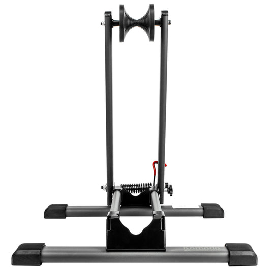 A black indoor cycling holder with a rear wheel mount and bottom bracket, shown against a solid white background.