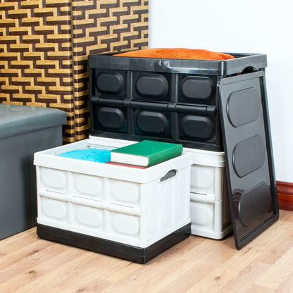A set of plastic folding storage bins in white and black, shown stacked and open on a wooden floor in a room setting.