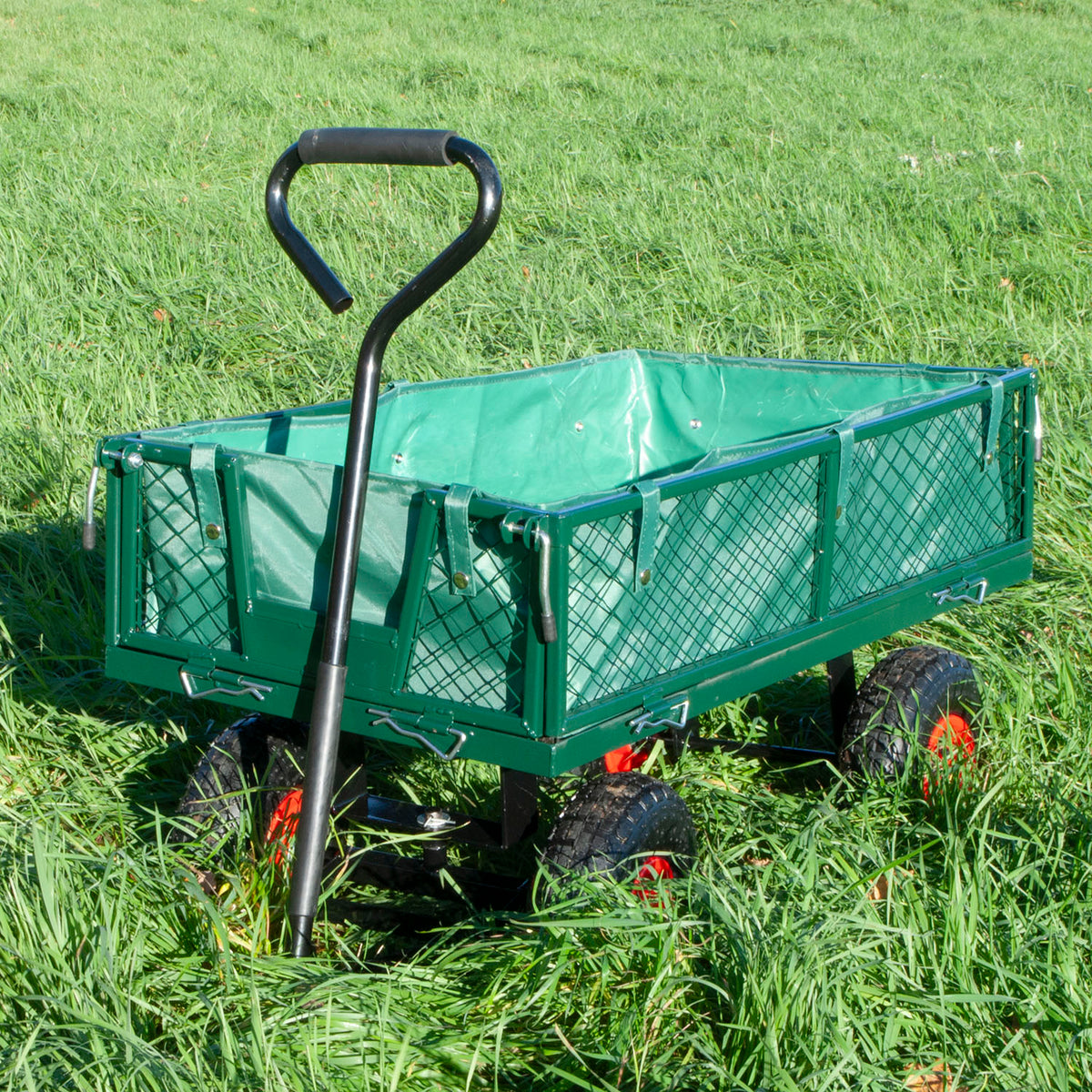 A green metal garden wagon with a black handle and mesh sides, shown on a grassy lawn.