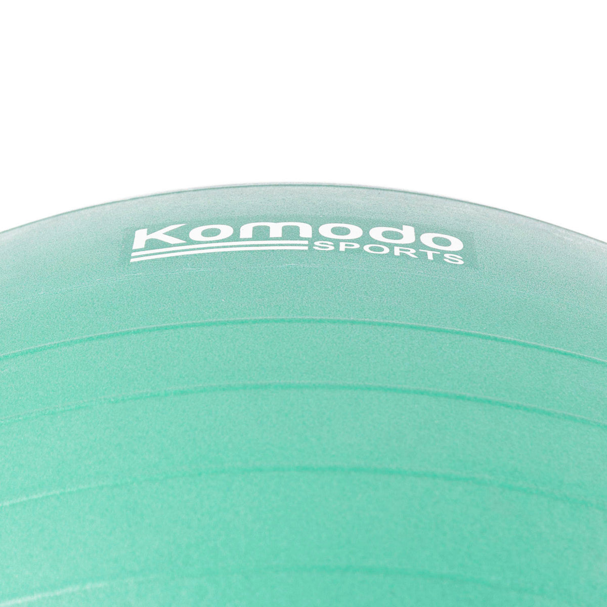 A close-up of a green exercise ball with the white 'Komodo Sports' logo printed on it, set against a plain white background.