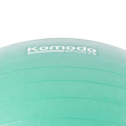 A close-up of a green exercise ball with the white 'Komodo Sports' logo printed on it, set against a plain white background.