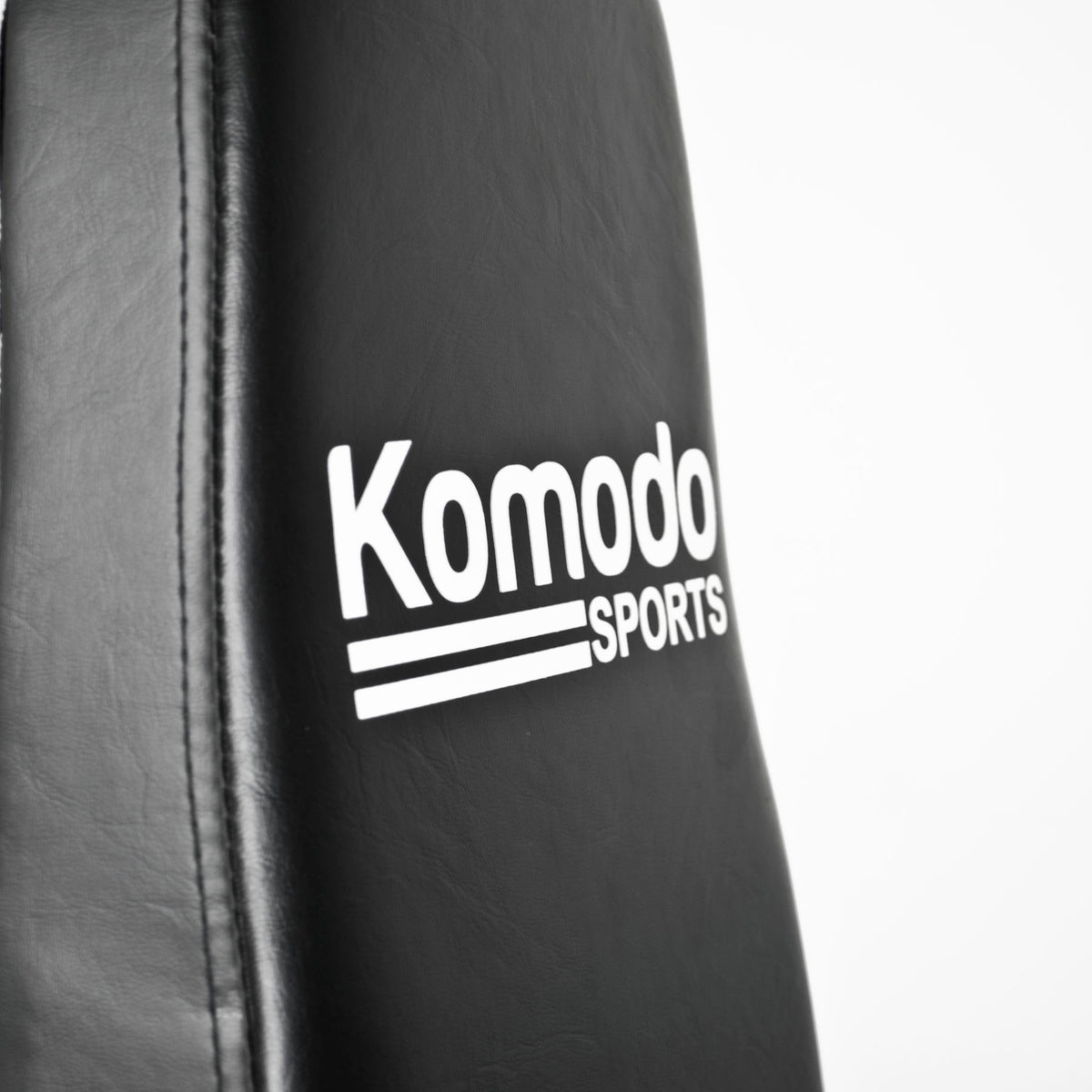 Close-up of a black padded training pad with white 'Komodo Sports' branding on a white background.