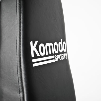 Close-up of a black padded training pad with white 'Komodo Sports' branding on a white background.
