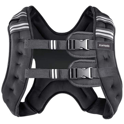 A black padded weighted vest with adjustable straps and plastic buckles, featuring white stripe accents on the shoulder straps, photographed on a solid white background. The brand name 'Komodo' is visible on a small label on the right side.
