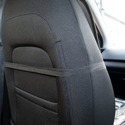 A close-up of a black car seat cover installed on a vehicle's backrest, with a horizontal support strap across the middle and a side belt loop visible.