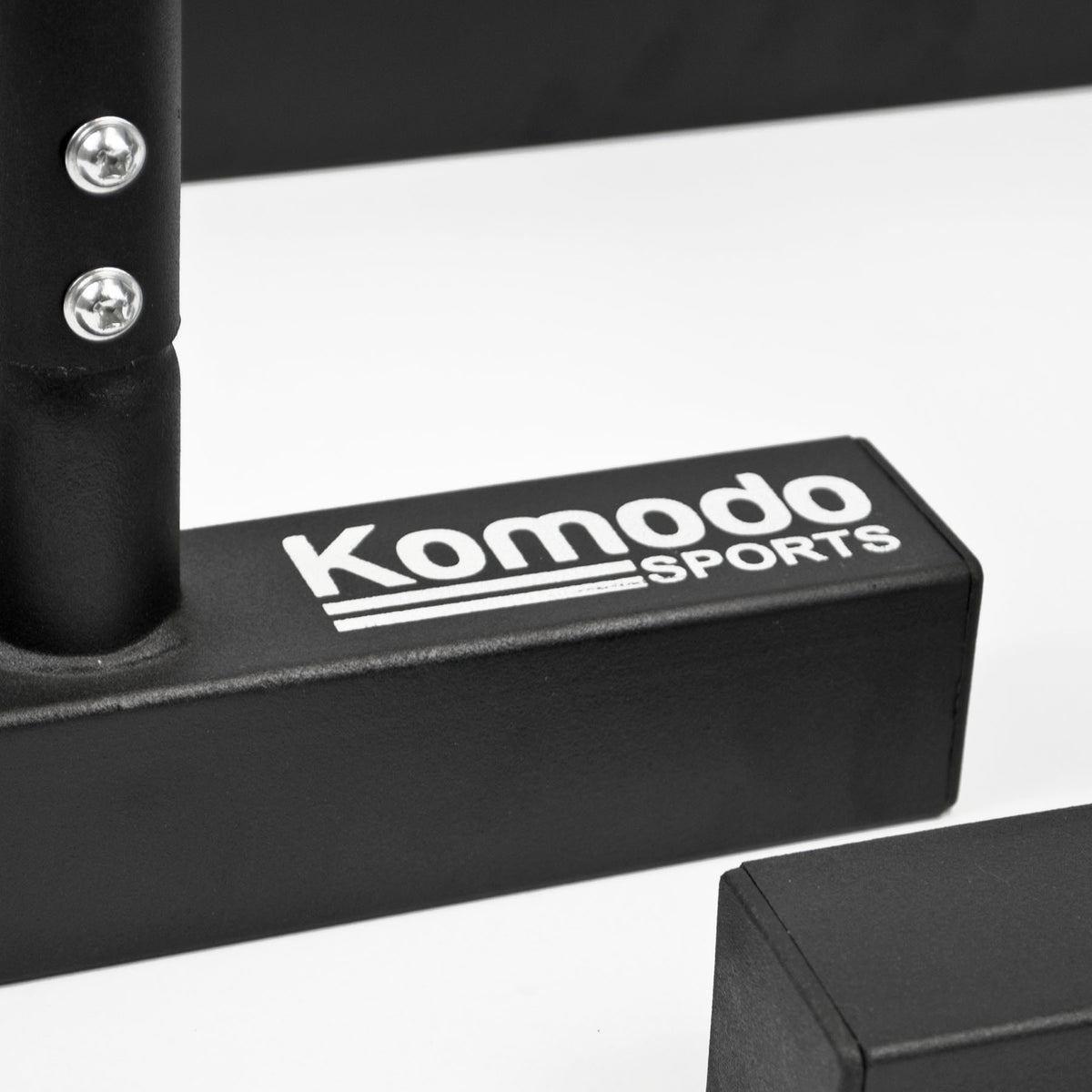 Close-up of a black gym accessory with the white printed brand name 'Komodo Sports' on a white studio background.