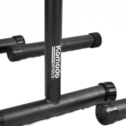 Close-up of a black metal gym stand with the brand name 'Komodo Sports' printed vertically in white on the center post, set against a clean white background.