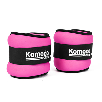 Two pink ankle weights with black straps featuring the white 'Komodo Sports' logo, shown on a clean white background.