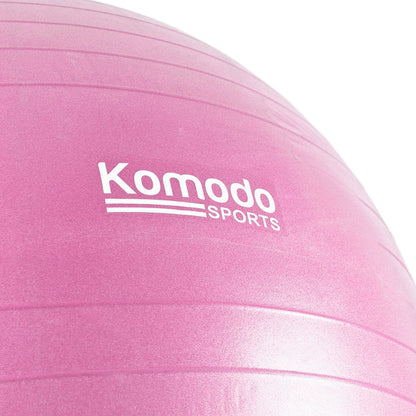 A close-up of a pink exercise ball with the white 'Komodo Sports' logo printed on the side, set against a clean white background.