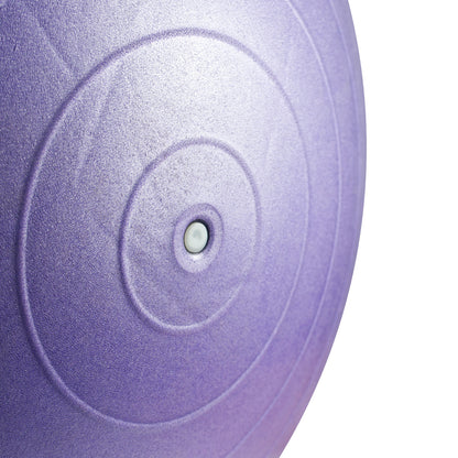 A close-up of a textured purple exercise ball with concentric circular grooves and a central metal weight pin, set against a plain white background.