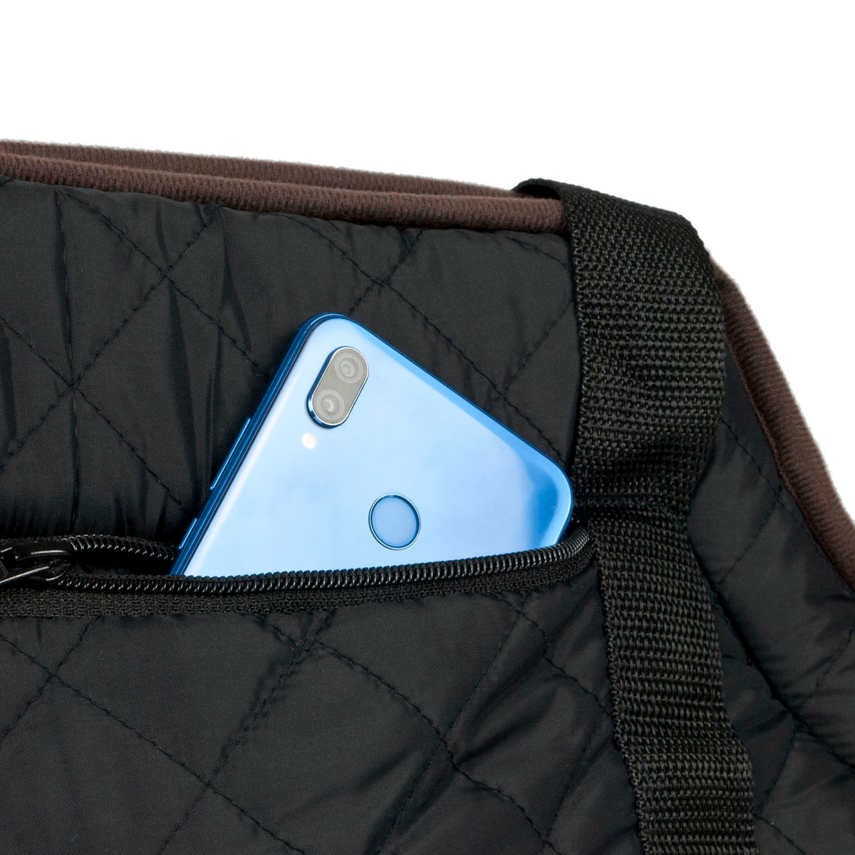 Close-up of a black quilted bag with a blue smartphone tucked into a front zipper pocket, showing the texture of the fabric and a brown trim edge against a white background.