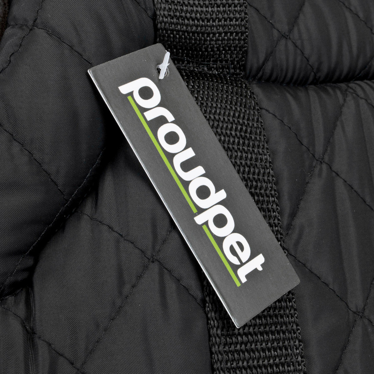 A close-up of a black quilted dog carrier with a black woven strap and a hanging tag that reads 'proudpet' in white with a green underline.