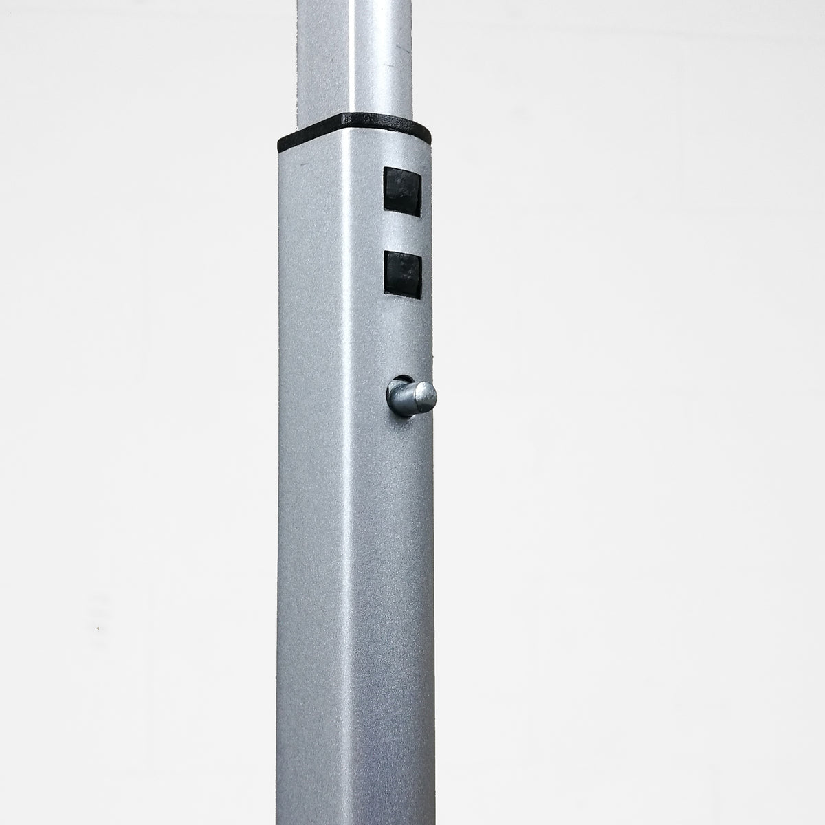 Close-up of a silver metal pole with black adjustment bands and a small silver knob, shown against a plain light gray background.