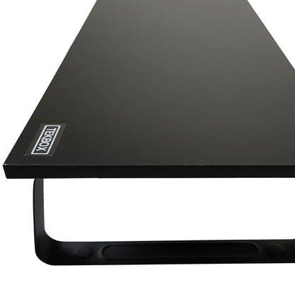 A close up of A black monitor riser desk. Witht eh brand name "TEKBOX" on the corner.