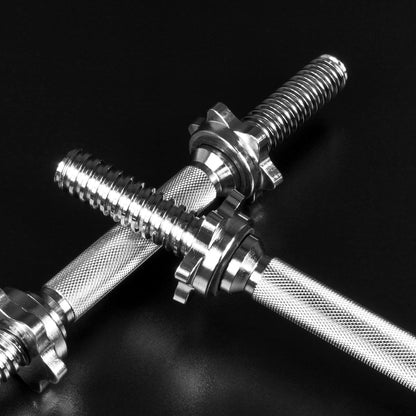Two metallic adjustable dumbbells crossed on a dark black background, showing knurled handles and threaded ends.