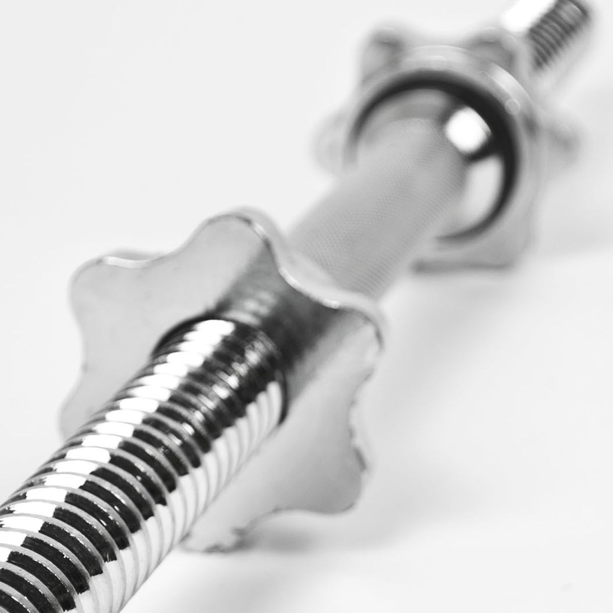 A close-up of a polished metal dumbbell with a knurled grip and star-shaped weight plates on a plain white background.