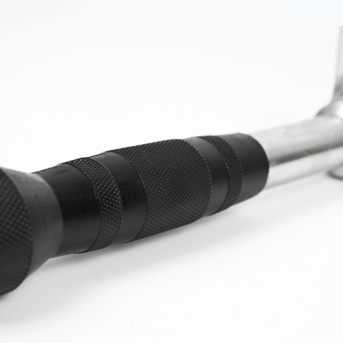 Close-up of a black textured grip handle on a metal bar, photographed on a clean white background.