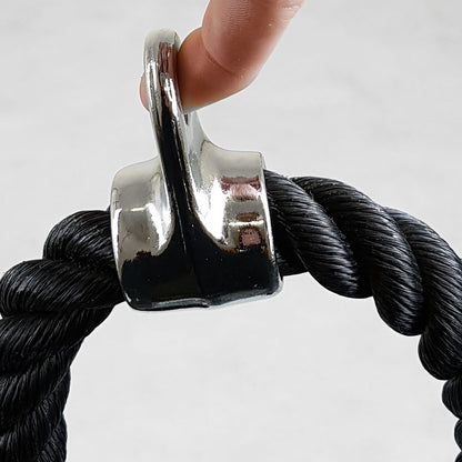 A close-up of a shiny silver metal cleat or hook attached to a thick black rope, with a human finger pressing down on the top loop against a light gray background.