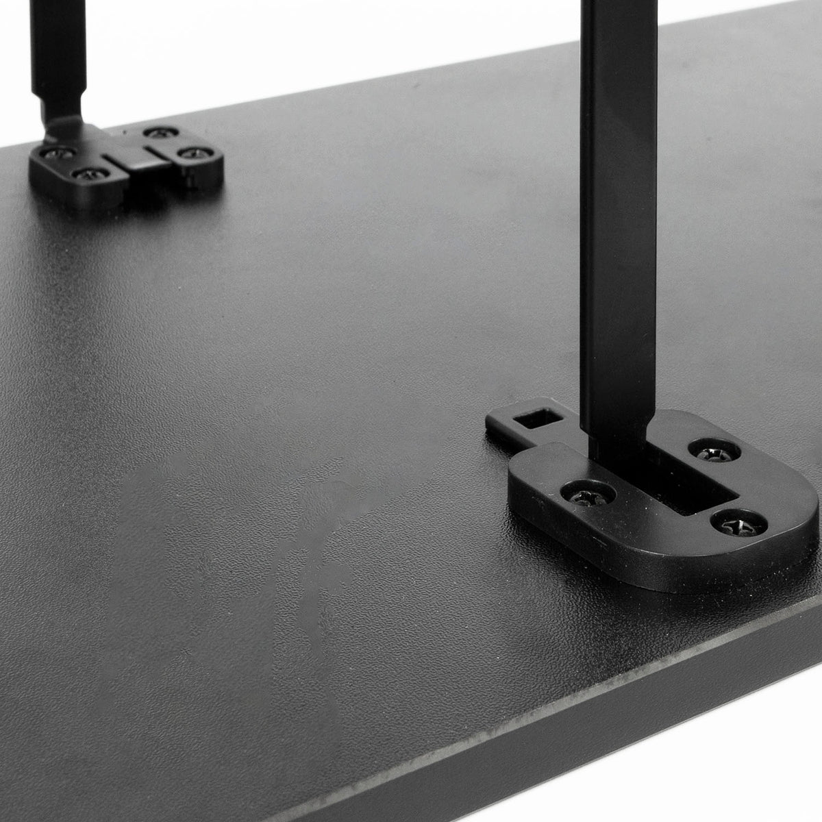 Close-up of a black monitor riser with metal support legs and mounting brackets on a white background.