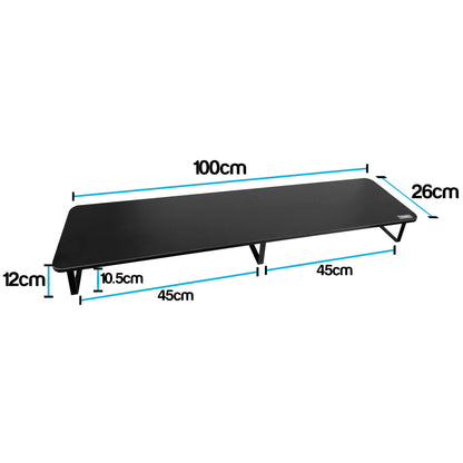 Black monitor riser shown on a white background with blue dimension lines and labels indicating 100cm length, 26cm width, 45cm depth, 12cm leg height, and 10.5cm tabletop-to-leg distance.