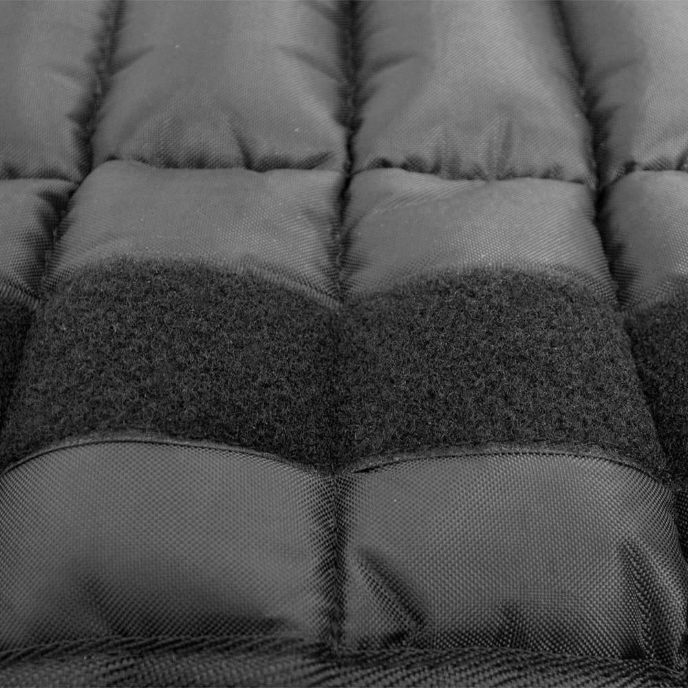 Close-up of a black weighted vest with stitched rectangular sections and a textured velcro-like band across the middle.