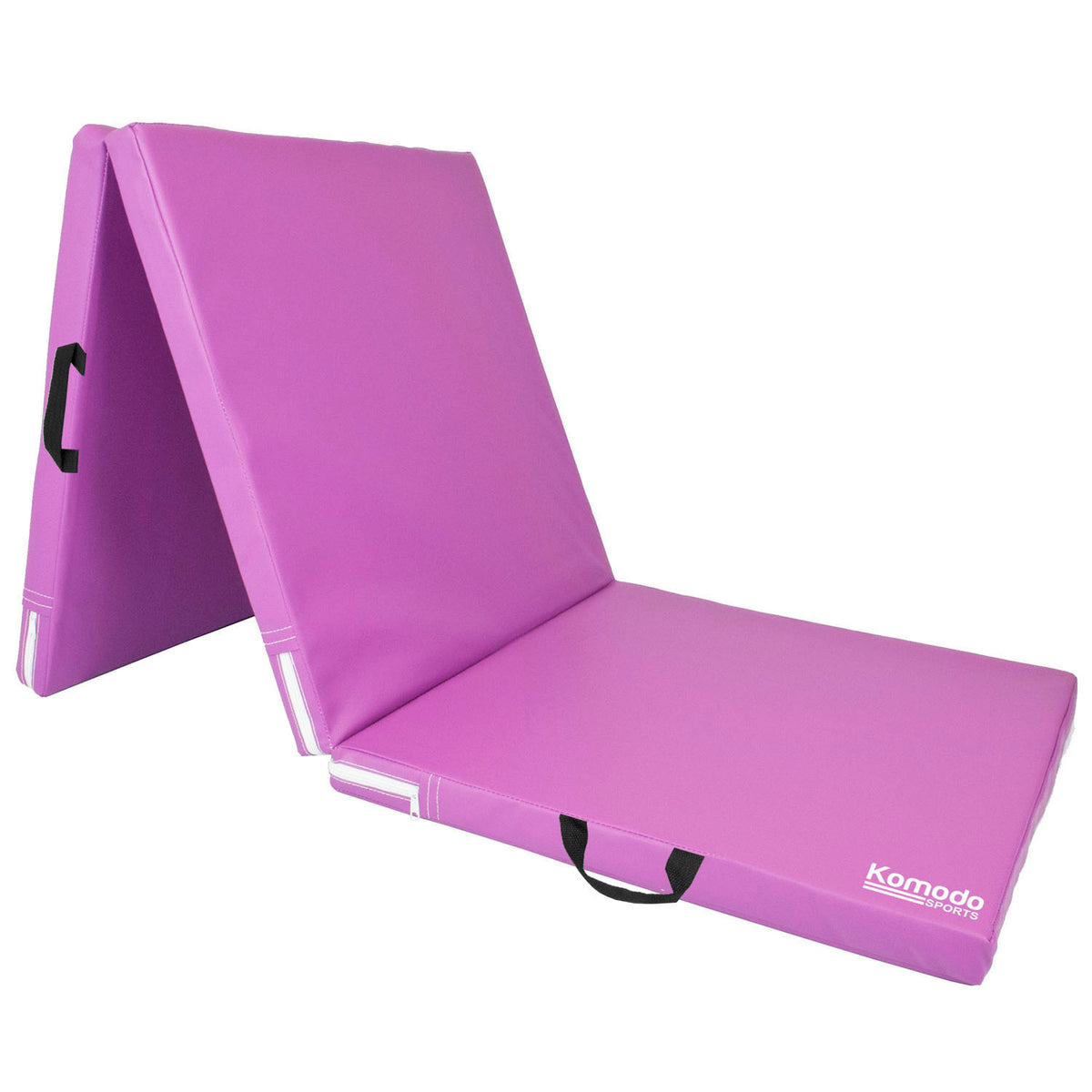 A purple yoga folding mat shown folded to display its thickness and carry handles, with the Komodo brand logo visible in the bottom right corner.