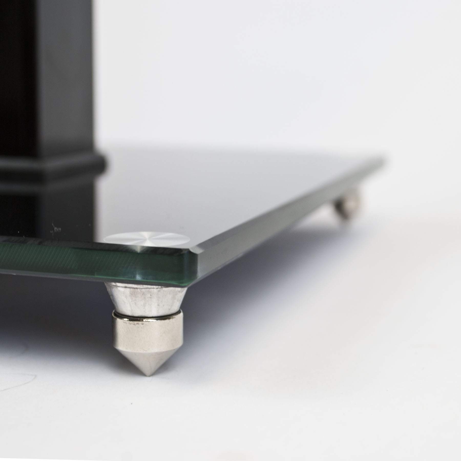 Two black glass speaker stands for surround sound with aluminium pillars and floor spikes on a white background